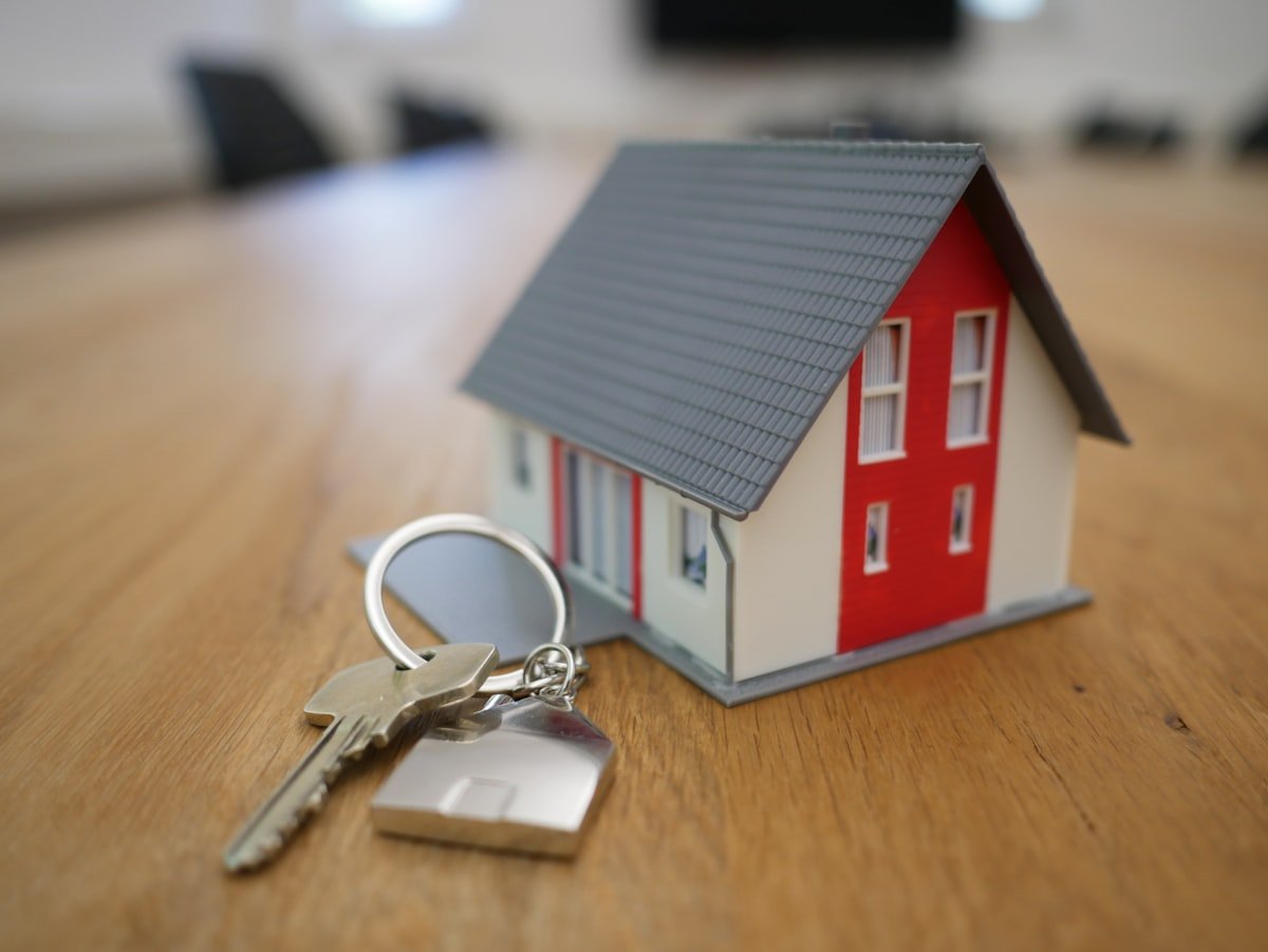 House keys on a keyring beside a model home